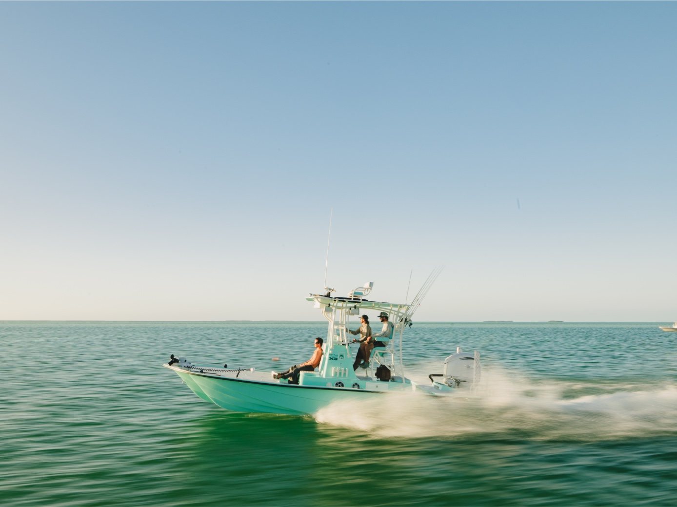 A center console boat runs fast across green water