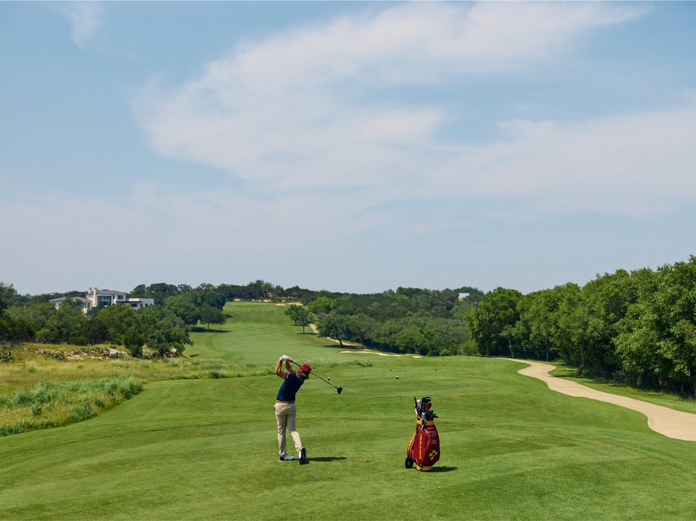 Cam Smith swings on a wide open fairway with his bag beside him