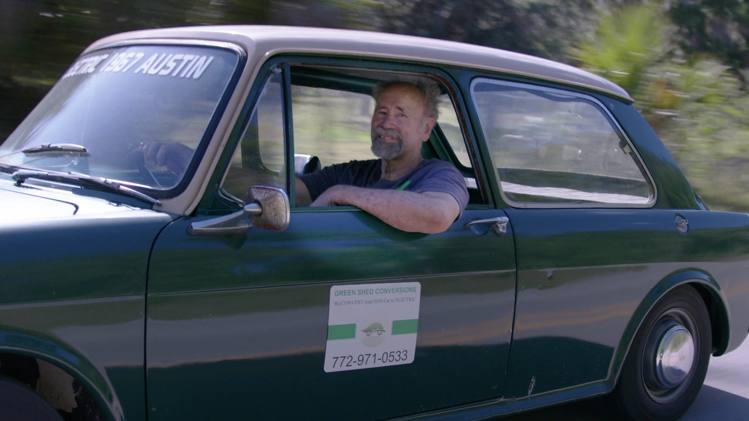 Steve Clunn smiling from the window of his electric 1967 Austin