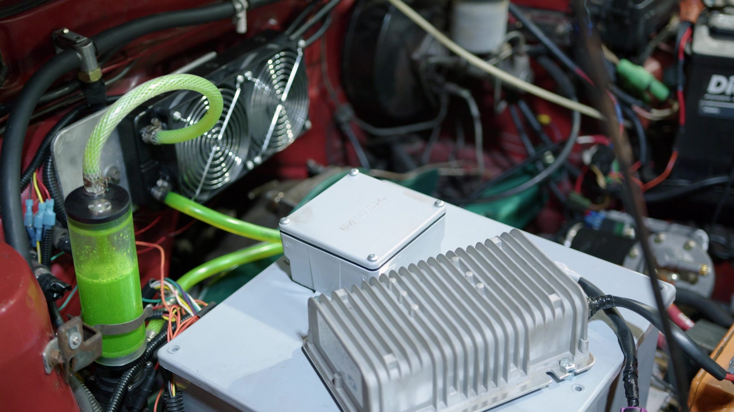 An EV controller and green coolant lines in a classic engine bay