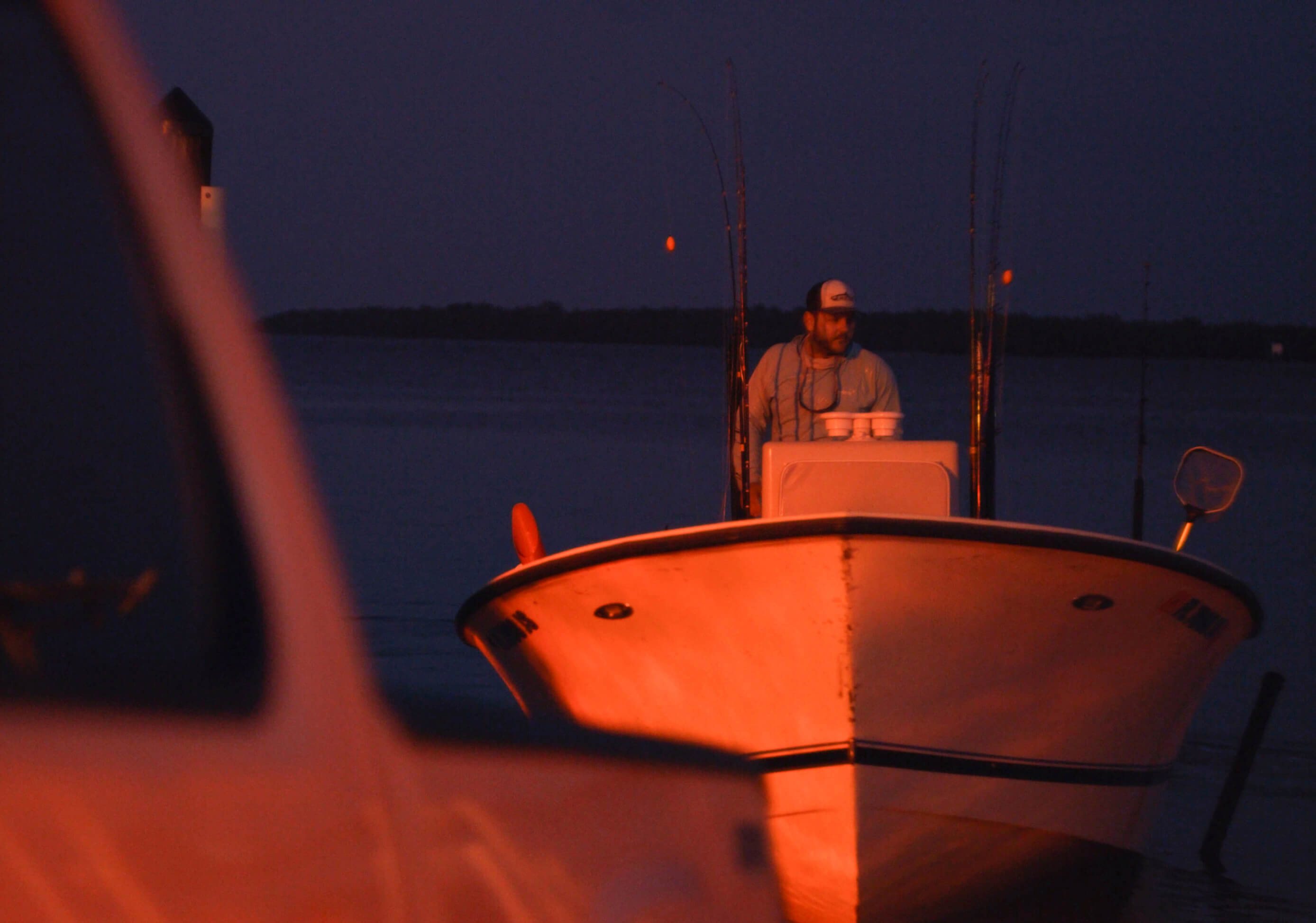 A fishing guide at the wheel of his boat before dawn