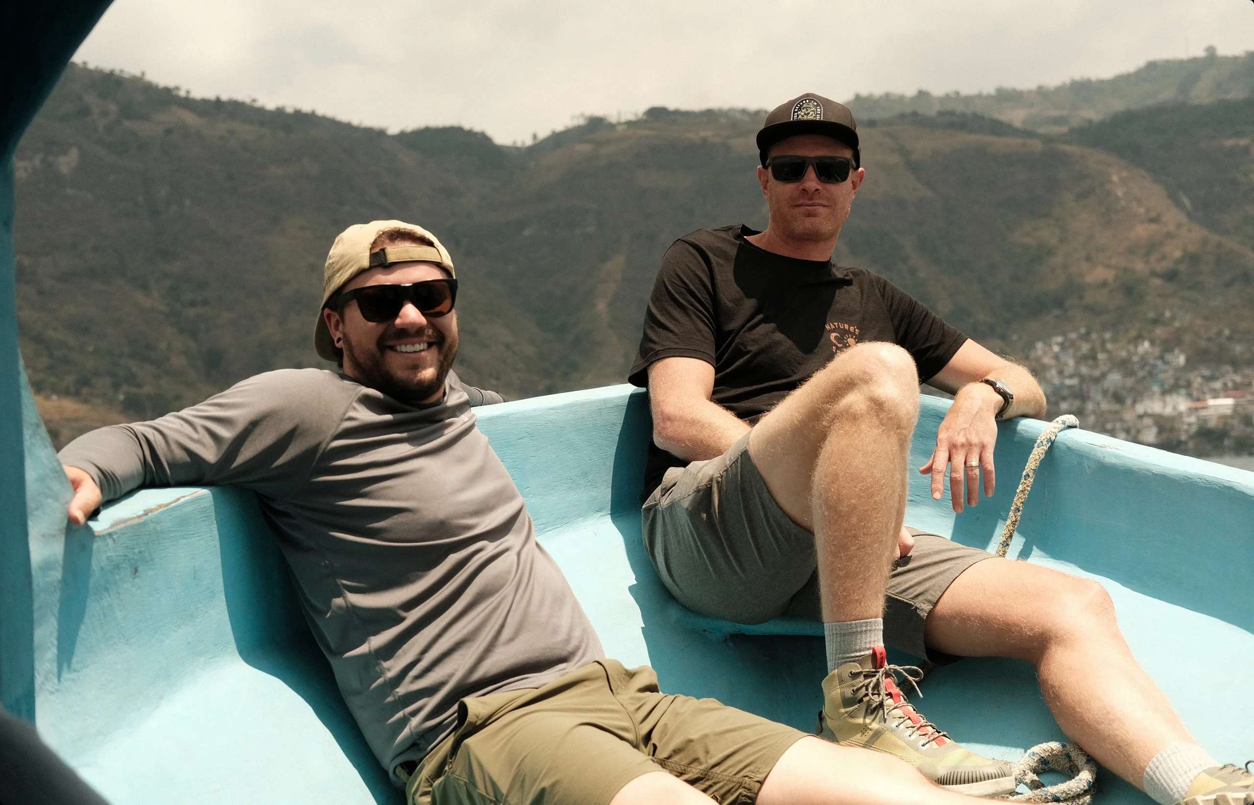 Derek and Josh leaning back in a small turquoise boat on the water