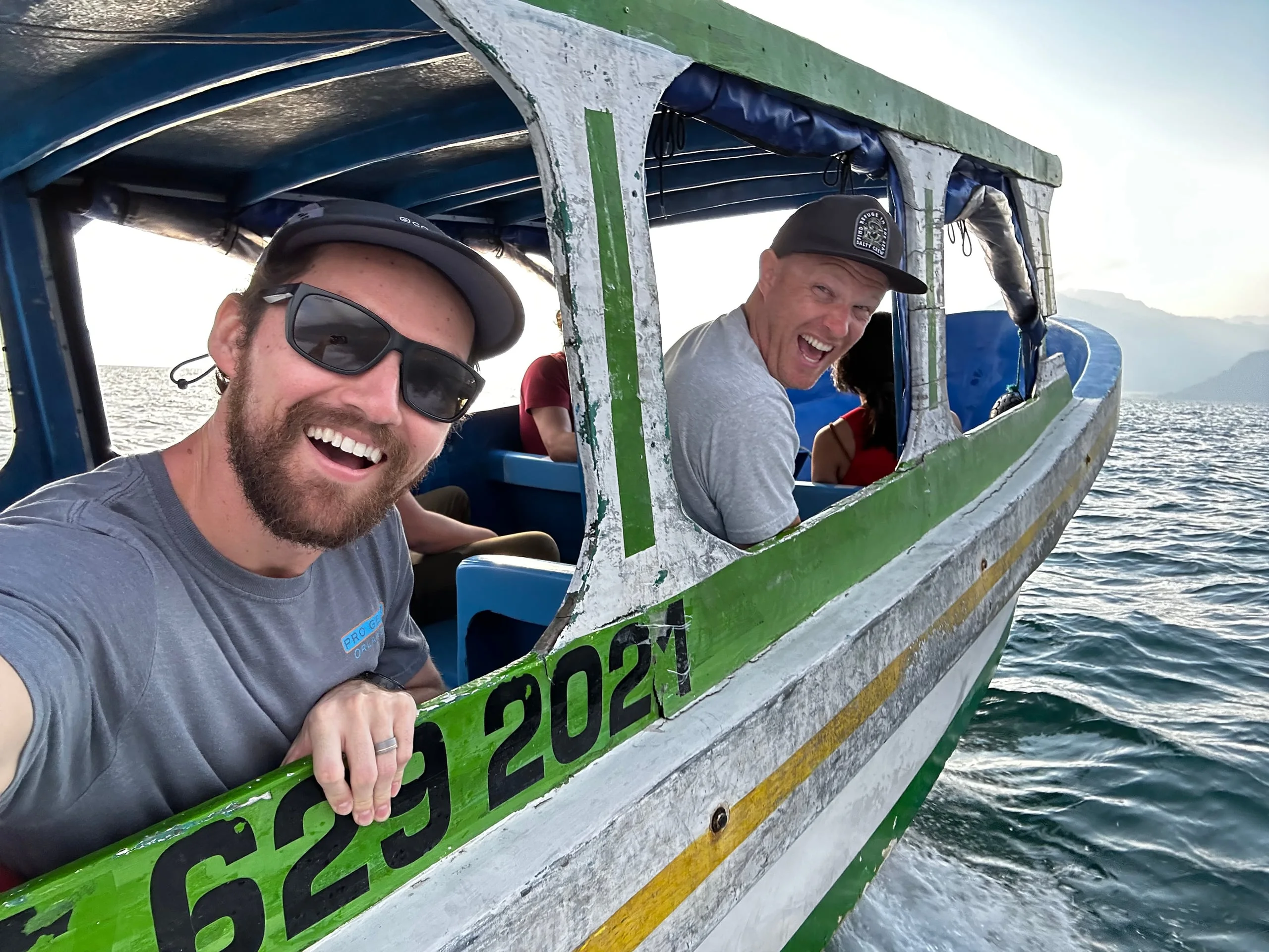 Derek and Josh grinning from a boat on the lake