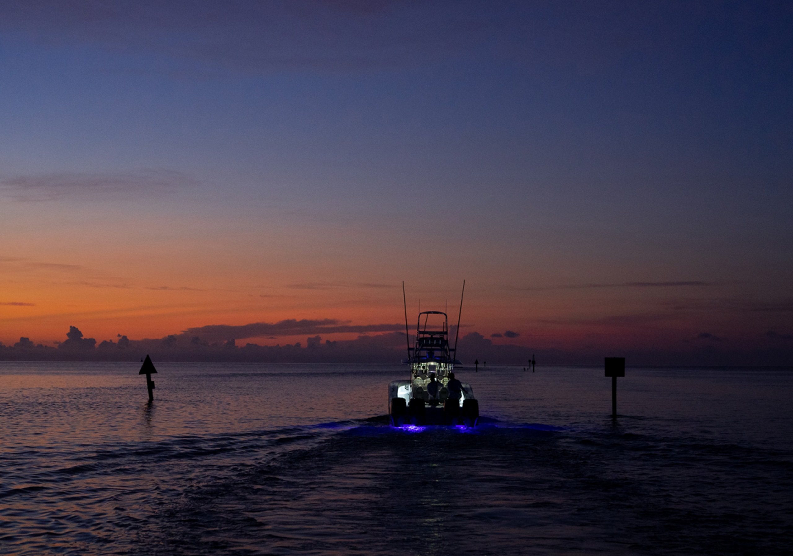 A fishing boat heads out at dawn off Islamorada, its underwater lights glowing