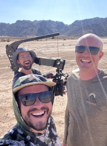 A crew selfie in the desert with a camera on a jib arm behind