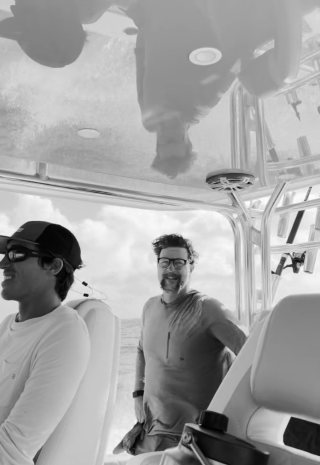 Two men smiling at the console of a boat under the T-top