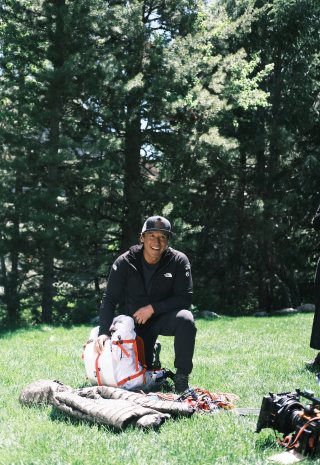 Jimmy Chin kneeling by his pack and gear on the grass