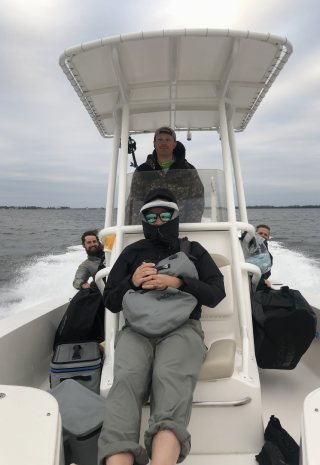 The crew bundled up in jackets riding in a boat as it speeds across the water