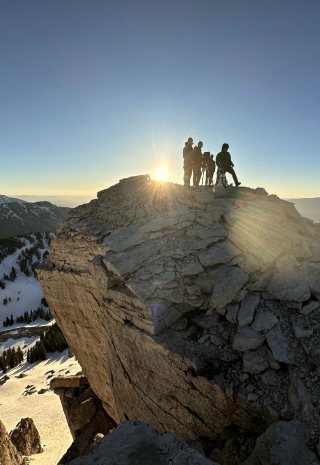 The crew silhouetted on a rock summit as the sun comes up