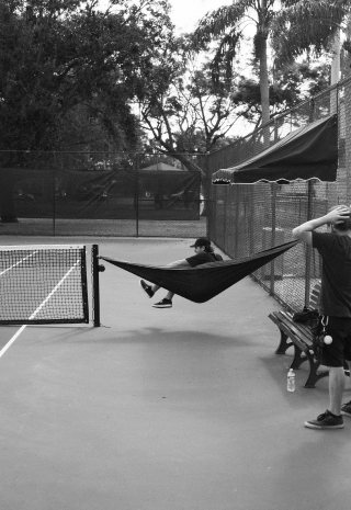 A crew member lounges in a hammock strung across a tennis net