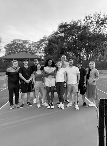 The cast and crew line up for a group photo on the tennis court