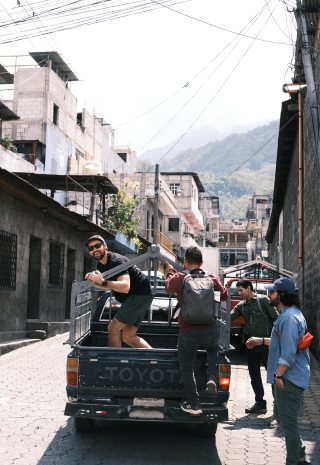 The crew loading gear into the back of a pickup on a steep town street