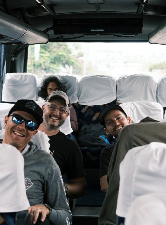 The crew smiling from their seats on a bus