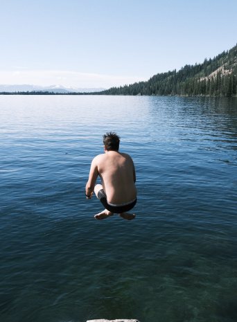 Someone cannonballing off a rock into a clear mountain lake