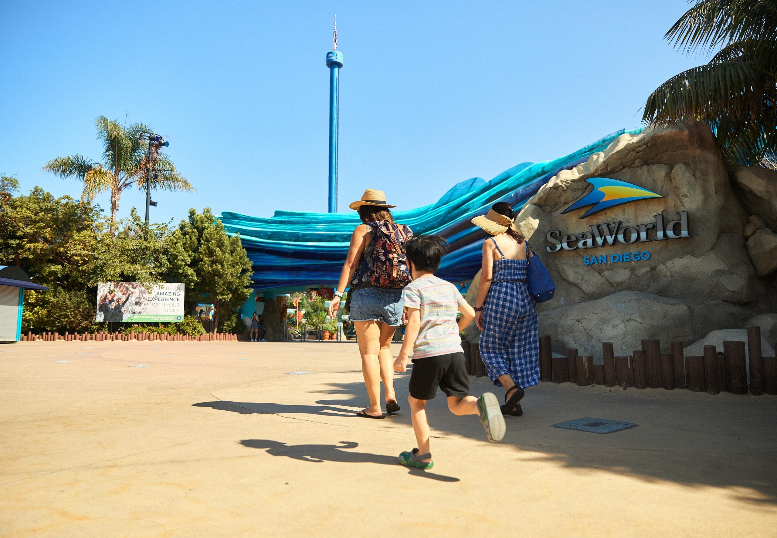 A family walks toward the SeaWorld entrance on a sunny day
