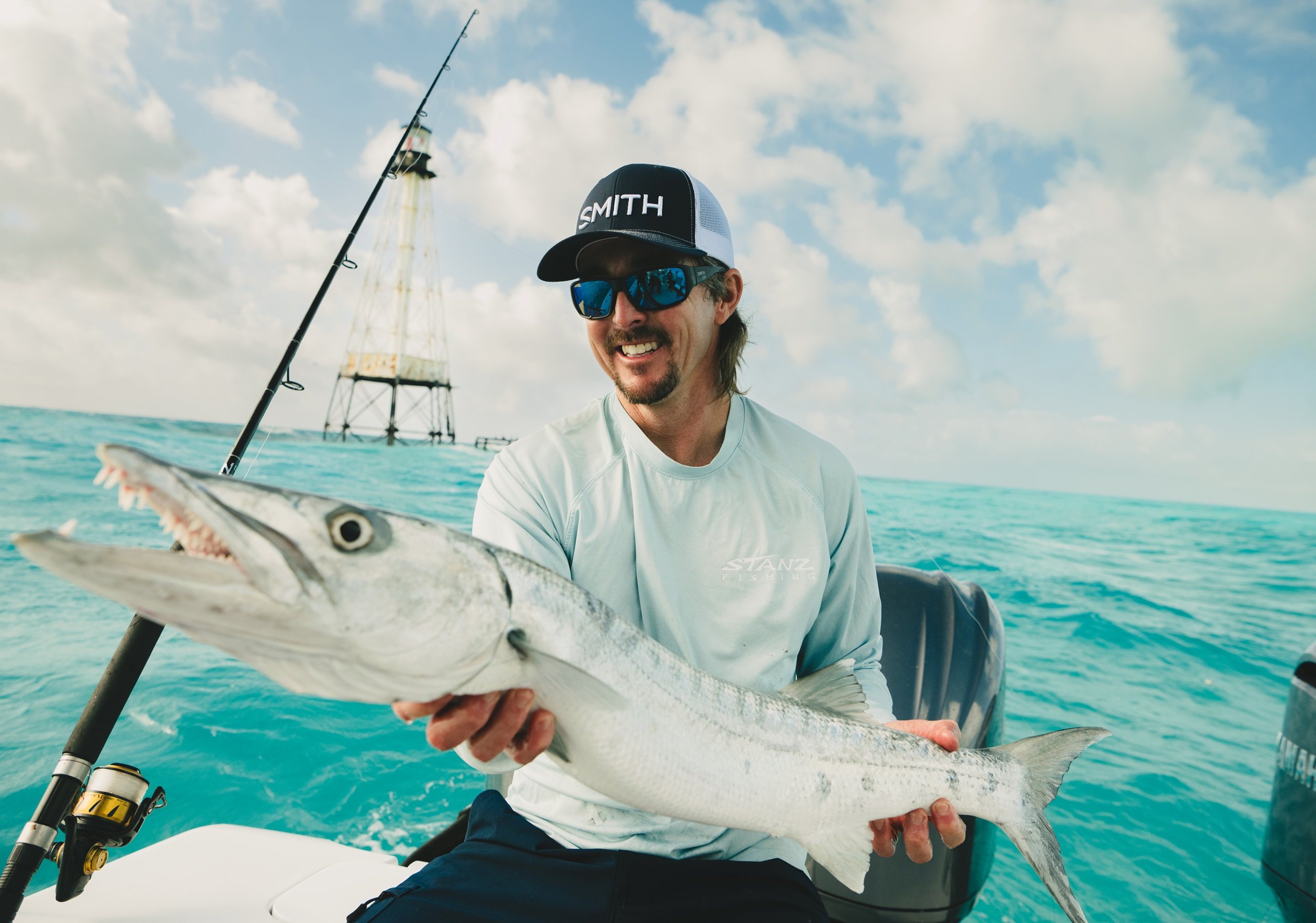 A fishing guide in SMITH sunglasses holds up a barracuda offshore