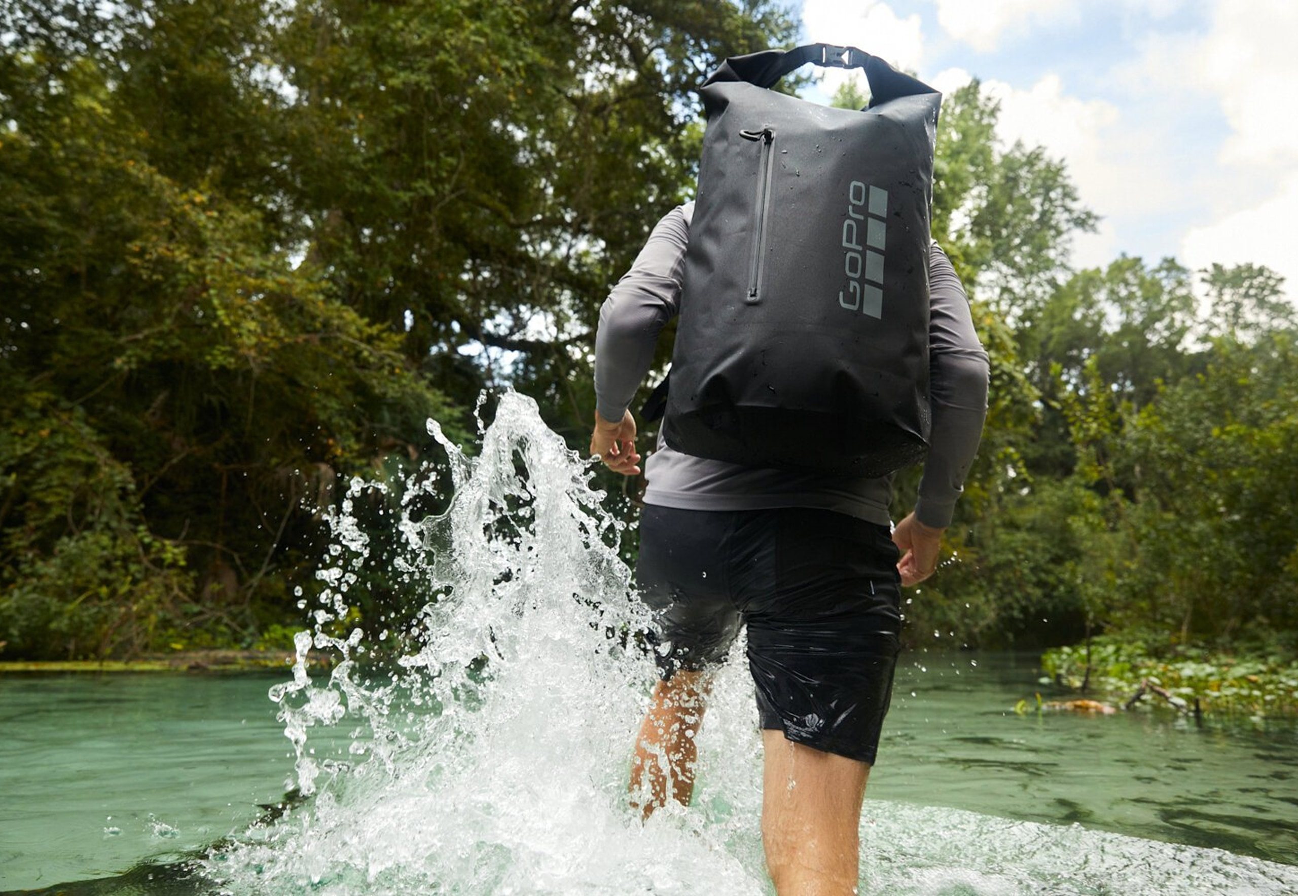 A man splashes into a spring wearing a GoPro dry bag