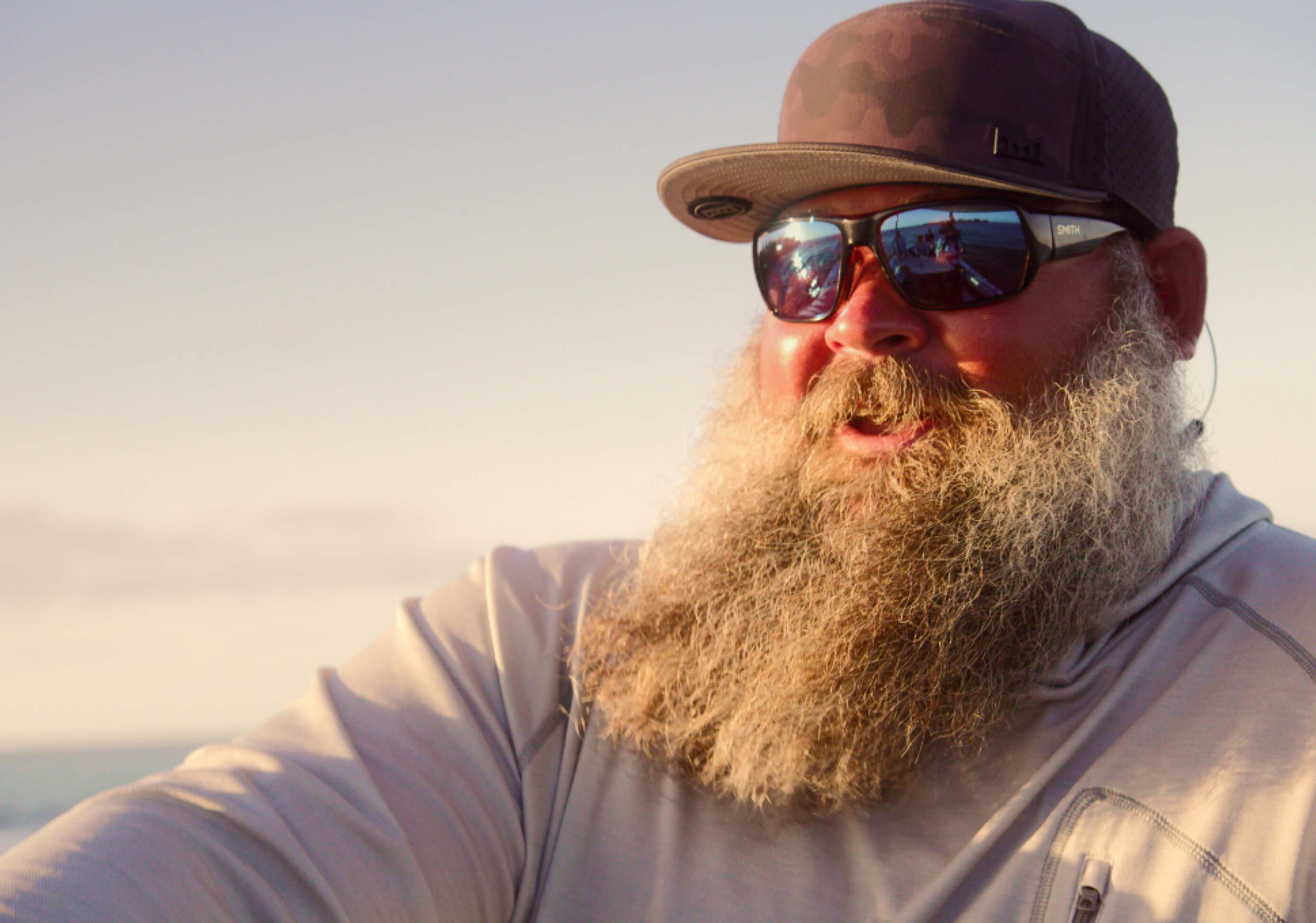 A bearded fishing captain in SMITH sunglasses at sunset